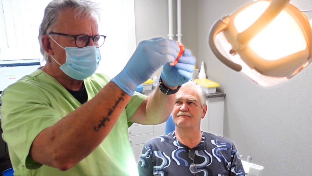 Tanntekniker inspiserer knekt proteser med pasient